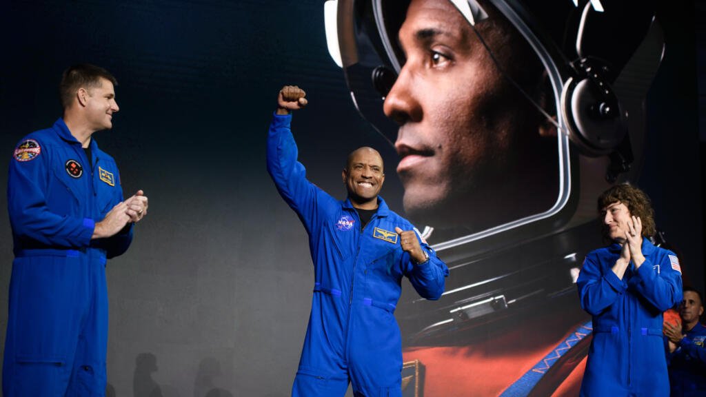 El piloto del Artemis II, Victor Glover (C), levanta el puño en el escenario.