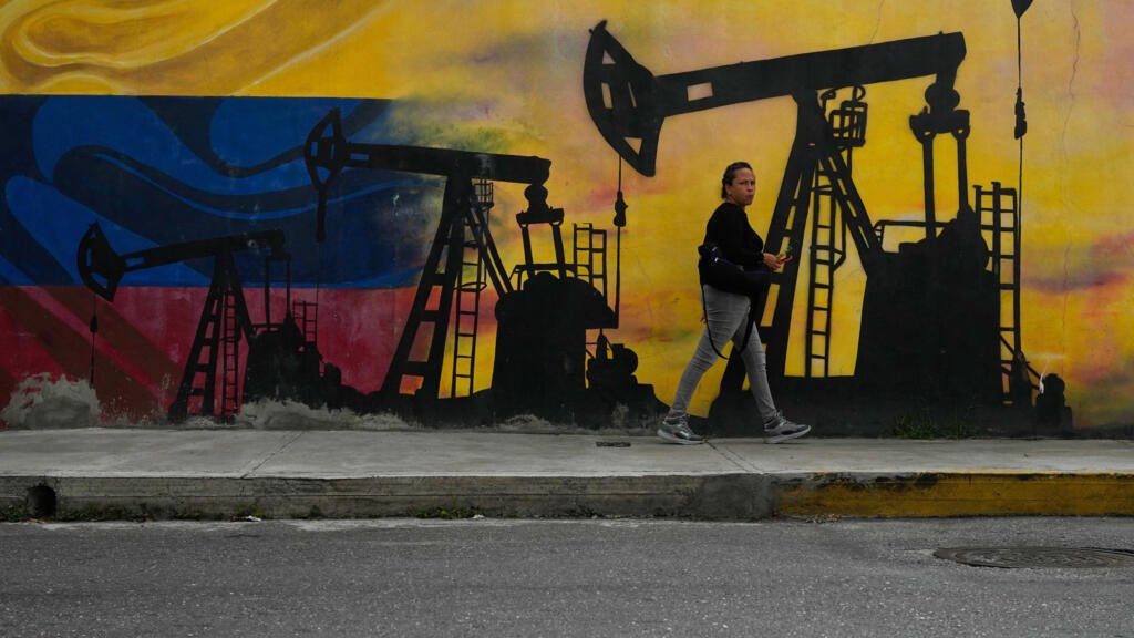 ARCHIVO - Un vecino pasa junto a un mural con bombas de petróleo y pozos en Caracas, Venezuela, 6 de enero de 2026.