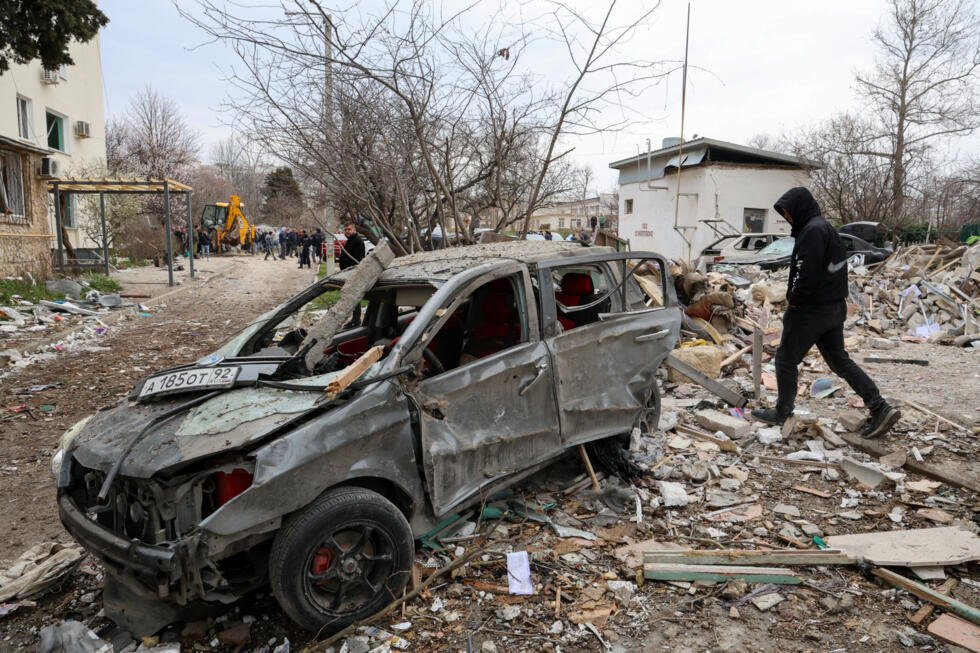 Foto de archivo. Un hombre pasa junto a un coche destrozado en el lugar de los hechos tras una explosión ocurrida durante la noche en un edificio residencial de varias plantas en Sebastopol, Crimea, el 24 de marzo de 2026.