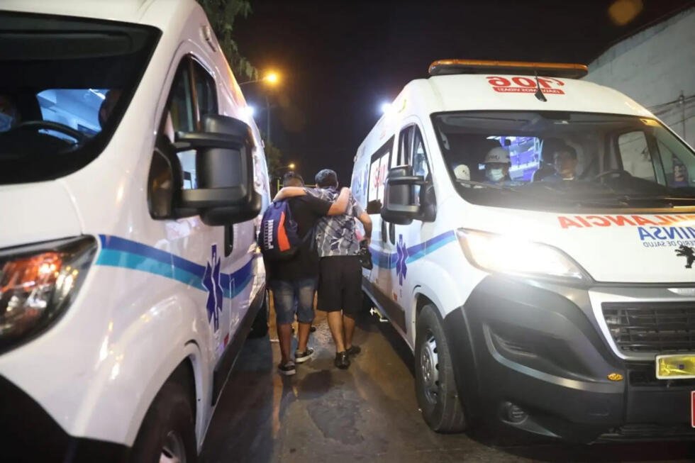 Fotografía cedida por la Agencia Peruana de Noticias Andina que muestra a personas caminando entre ambulancias estacionadas afuera del Estadio Alejandro Villanueva este viernes, en Lima (Perú).